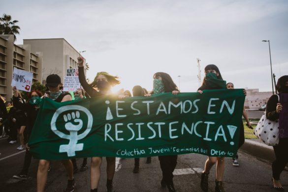 Grupo de manifestantes sosteniendo una pancarta con el texto "estamos en resistencia" en una protesta.